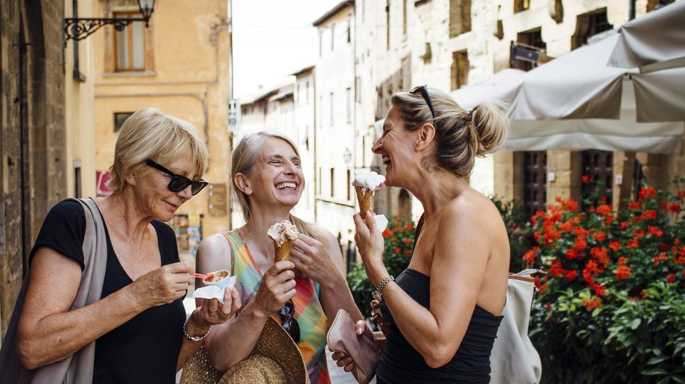 Three happy women eating icecream in town